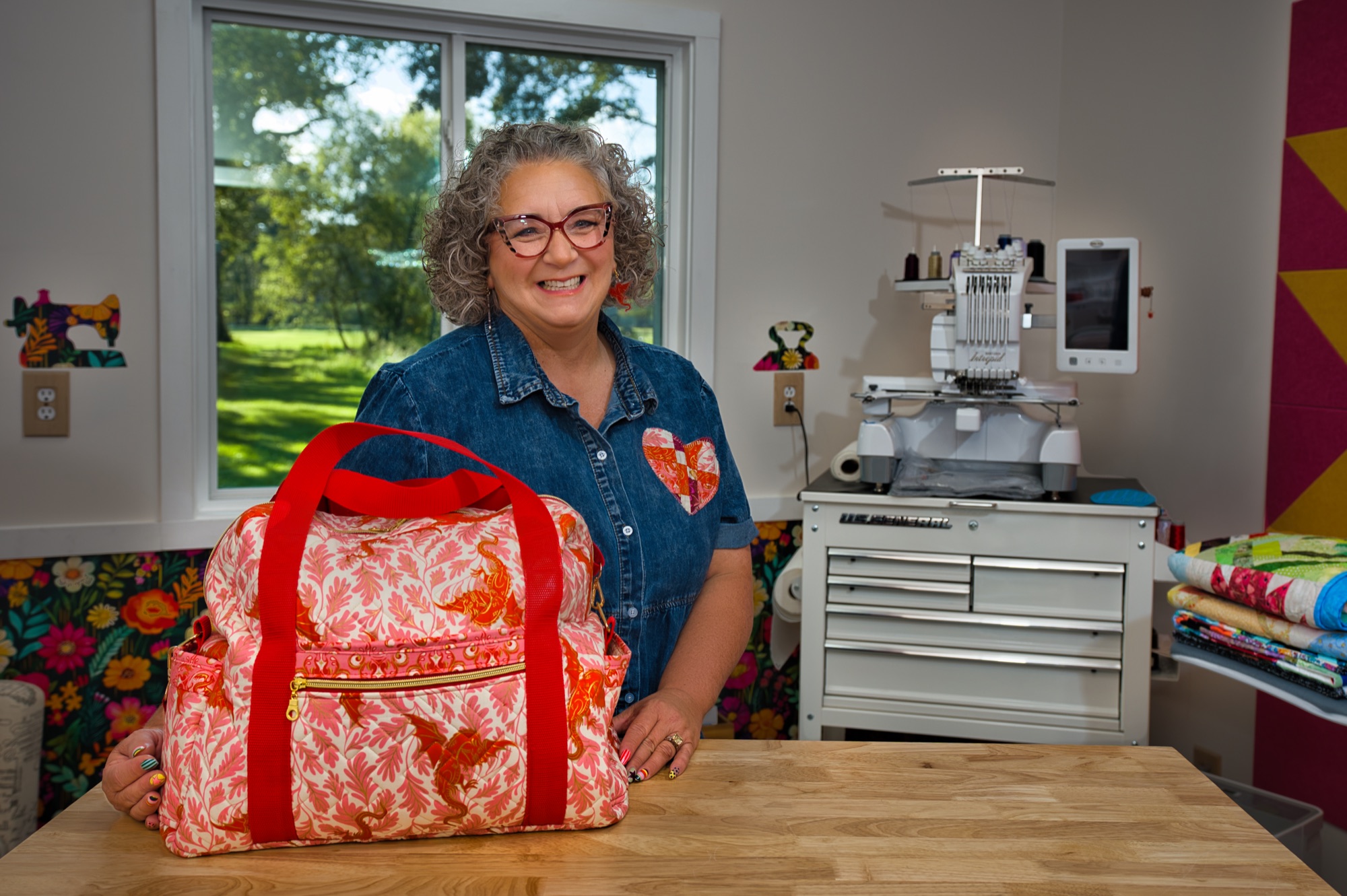 Angela standing behind a large handmade bag in coral floral fabric on her cutting table