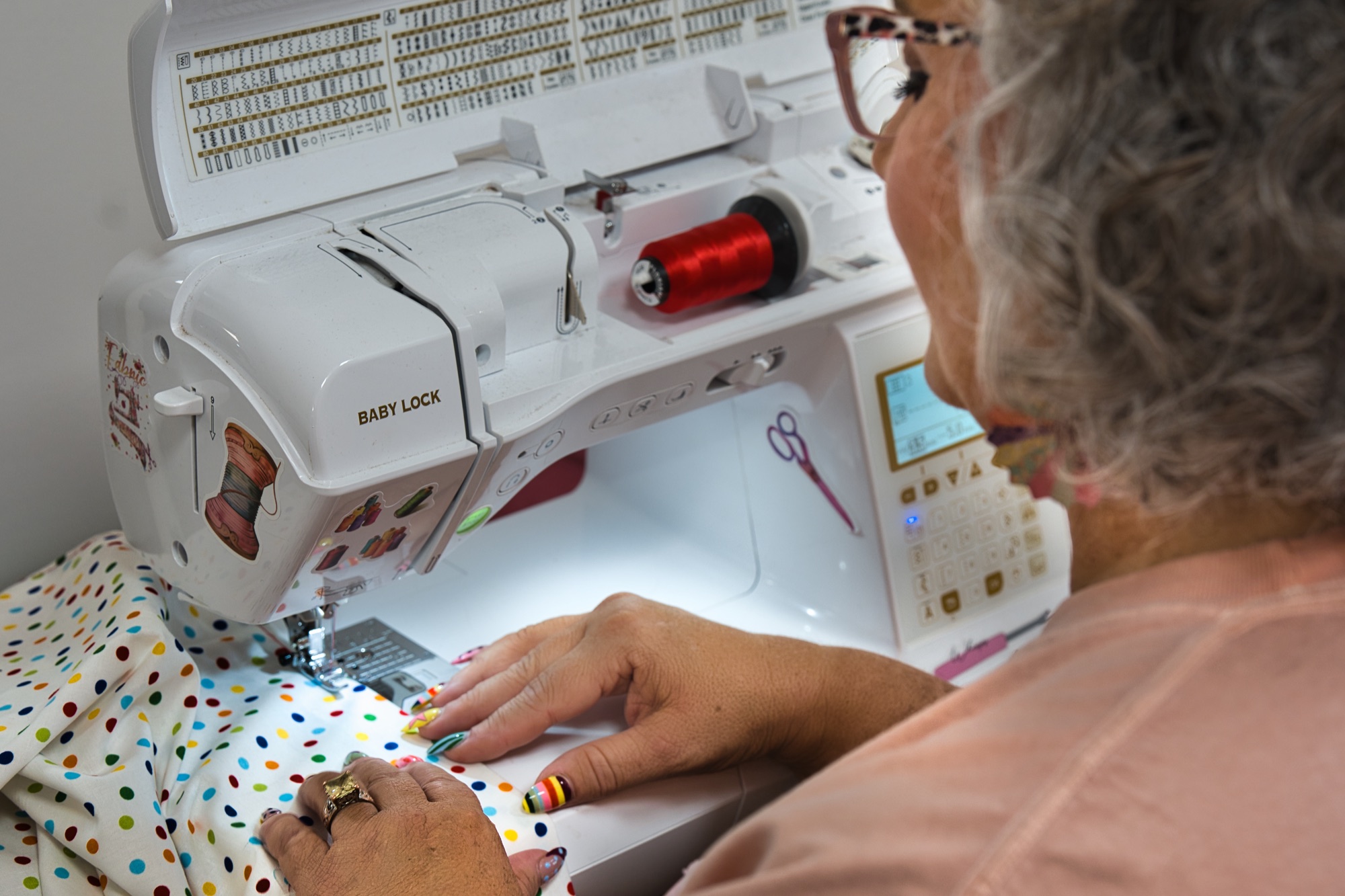 Hands guiding polka dot fabric through a sewing machine