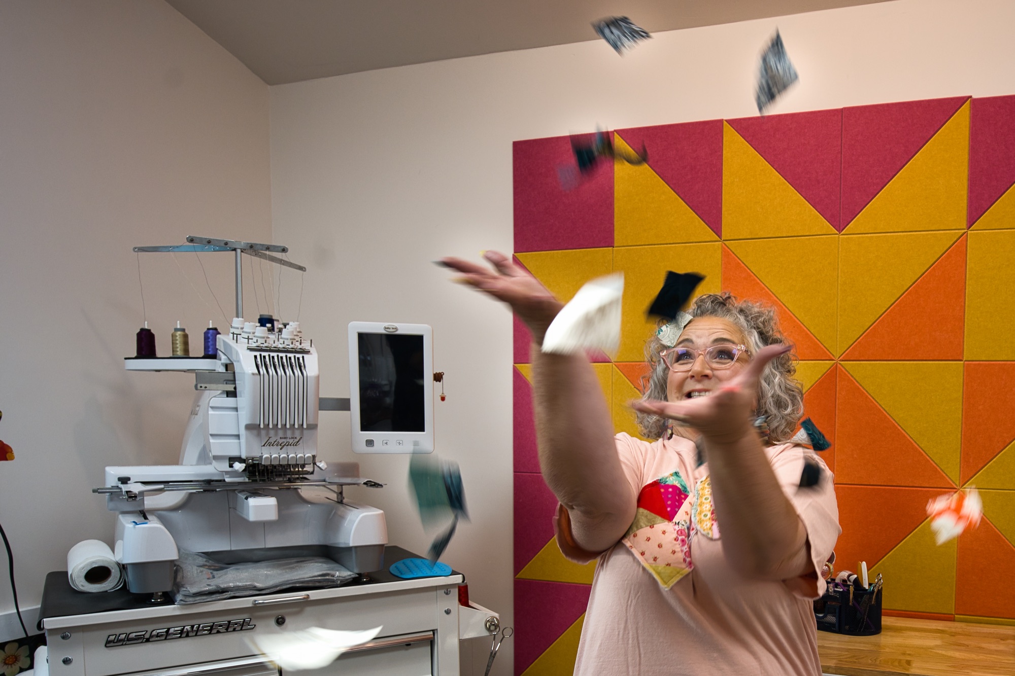 Angela laughing as she tosses fabric squares into the air in her she shed