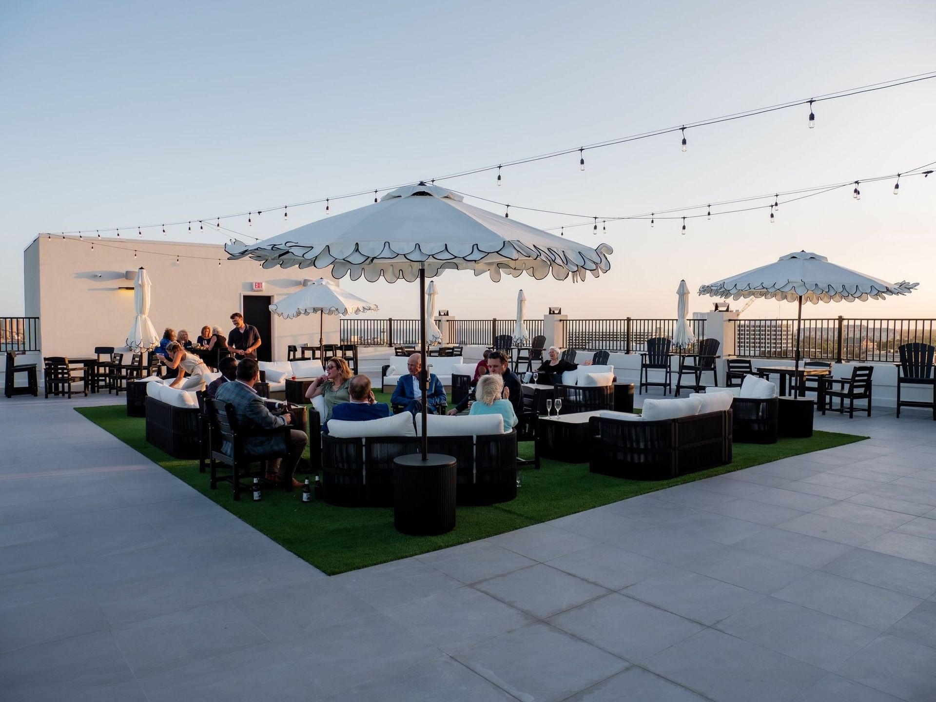 The rooftop terrace of the Markham Hotel at dusk, with white scalloped umbrellas and string lights